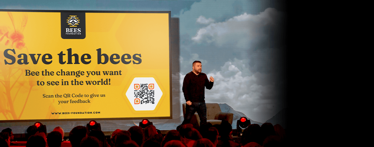 A man from fictional non-profit brand, Bees Foundation, prompts an audience to scan the QR Code image.